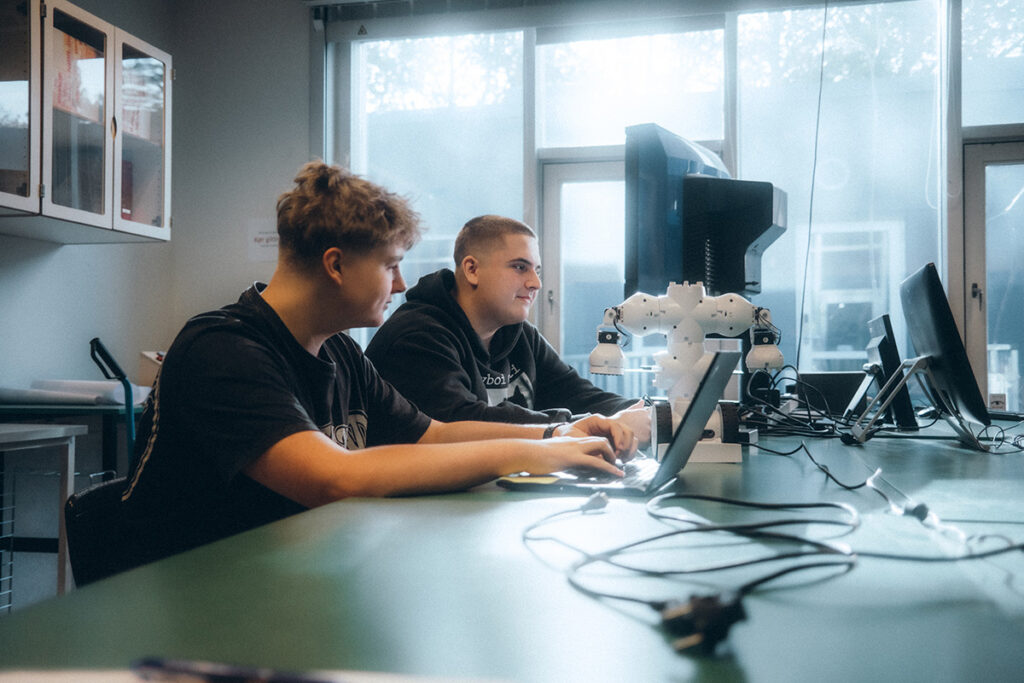 Elever, drenge programmerer en lille robot på studieretningen Programmering på Pulsen Gymnasium