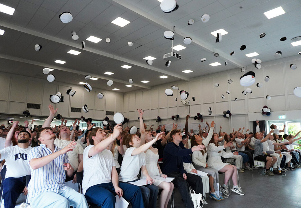 Nybagte studenter kaster studenterhuer op i luften i salen til translokationen på Pulsen Gymnasium